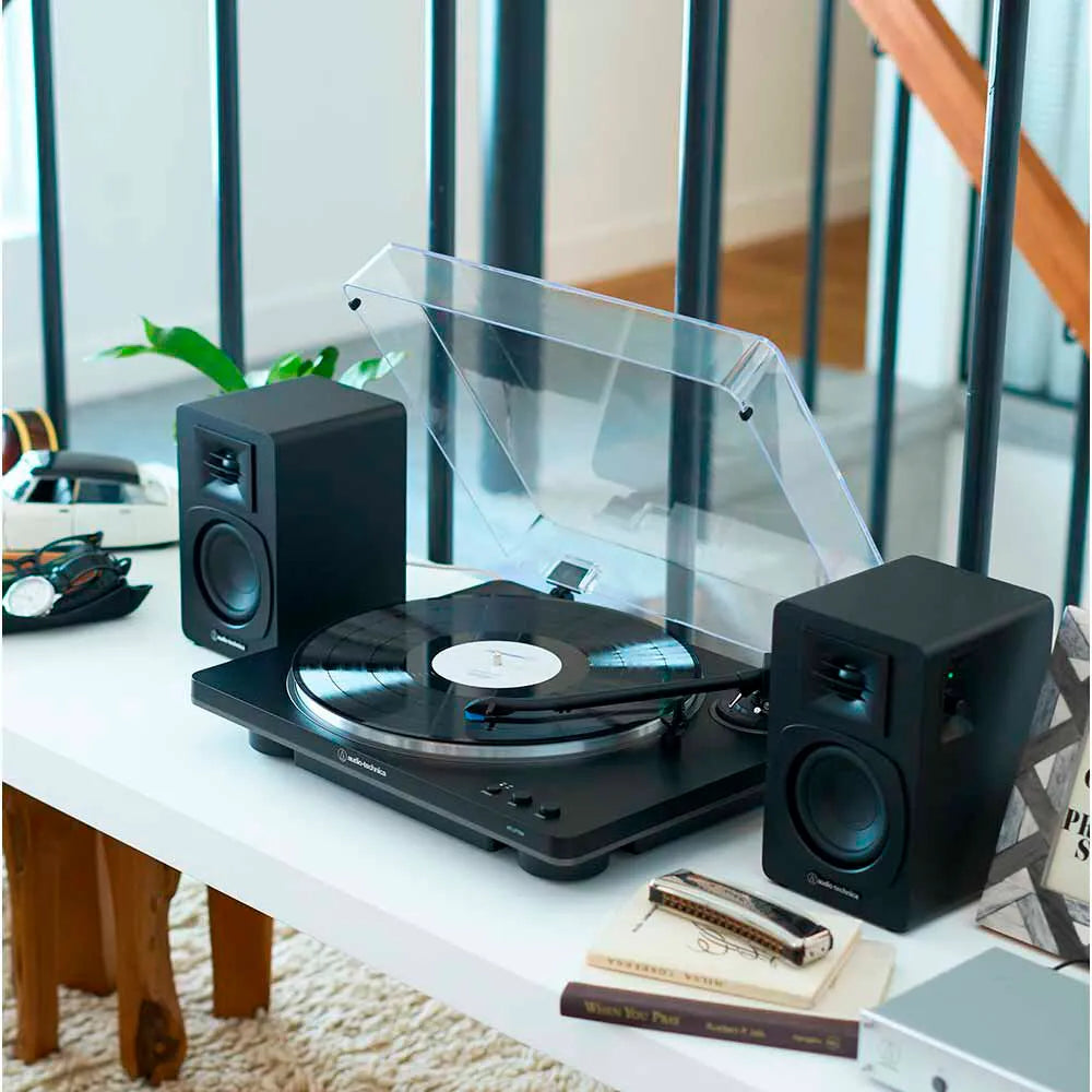 Tornamesa Automática AT-LP70XBT negra/plateada y Altavoces Bluetooth AT-SP3X negros en un escritorio